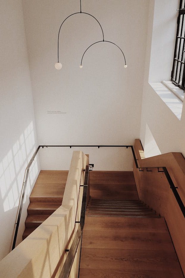 A minimalist interior featuring a wooden staircase with natural lighting and modern design elements.